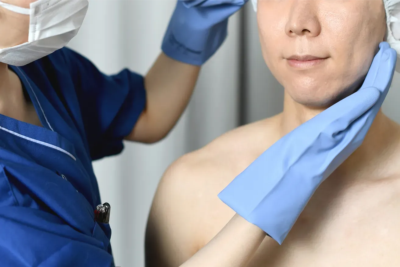 Plastic surgeon examining man’s face