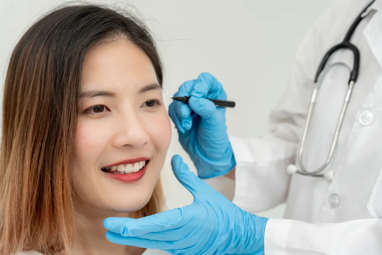 Plastic surgeon assessing patient’s face while applying contour lines