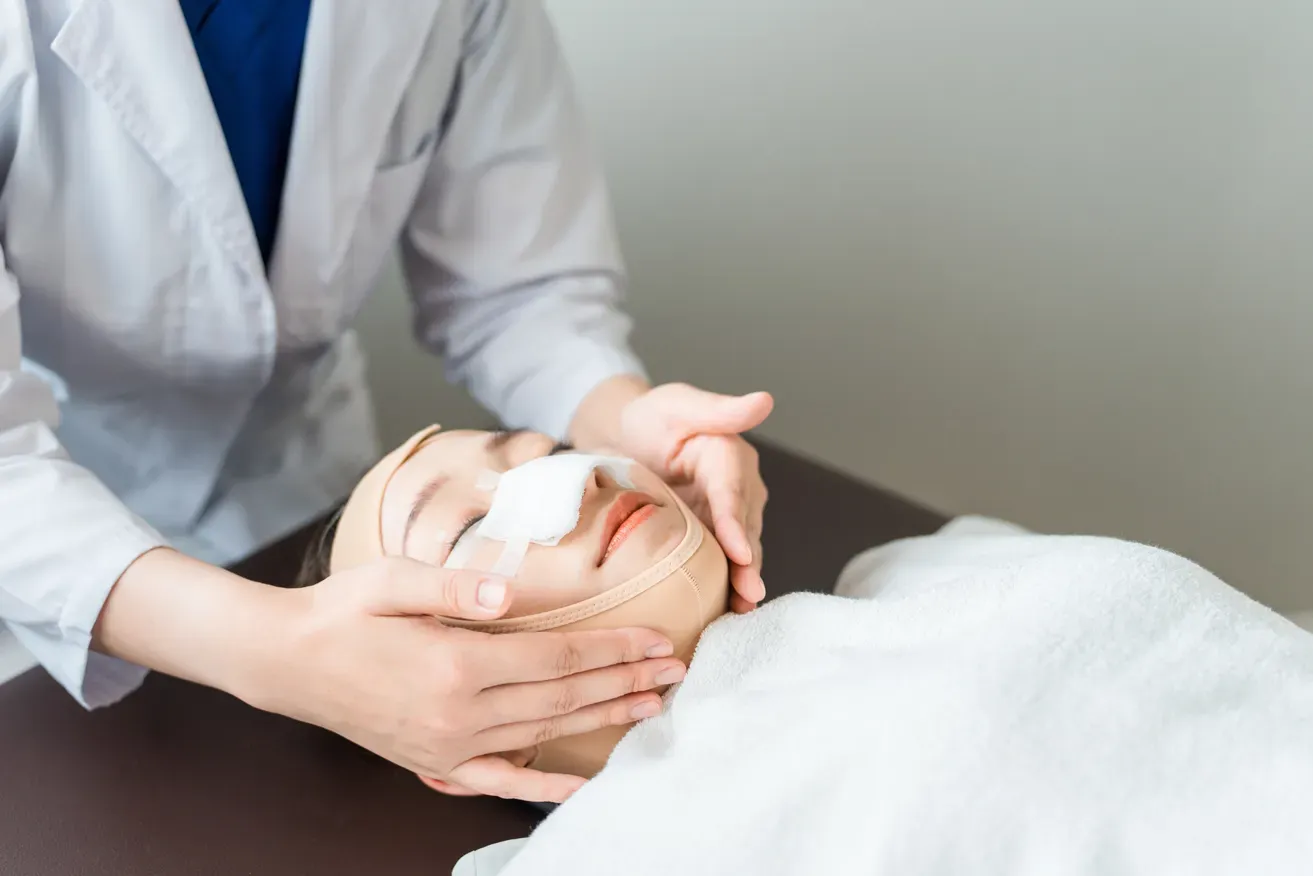 Woman lying on bed recovering from plastic surgery
