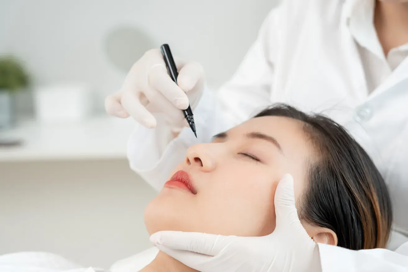 Plastic surgeon marking a woman’s nose during a rhinoplasty consultation